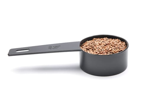 Linseed in measuring spoon on white background