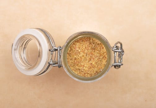 Wheat germs in open jar on brown background