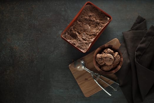 Chocolate ice cream scoop, scooped out of a container with a silver utensil