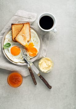 Breakfast served with fried eggs, bread, jam, butter and coffee on the table top view. Heathy breakfast food