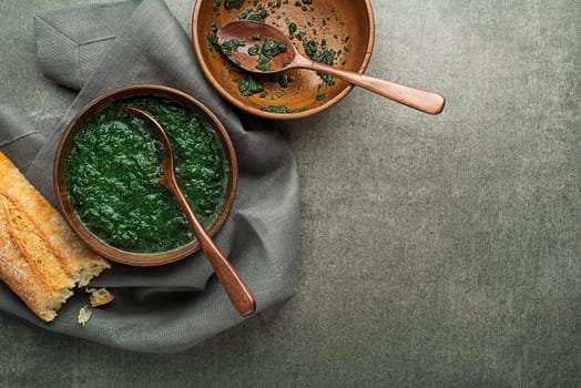 Eating spring healthy meal. Green creamy soup with vegetables and herbs and bread