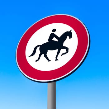 Road sign to prohibit passage with horse on sky background.