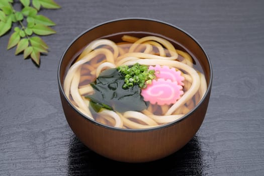 Japanese Kake udon noodles in a bowl on black background