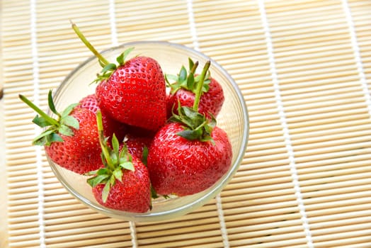 Fresh strawberries in a bowl on bamboo background