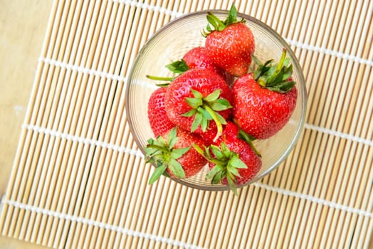 Fresh strawberries in a bowl on bamboo background