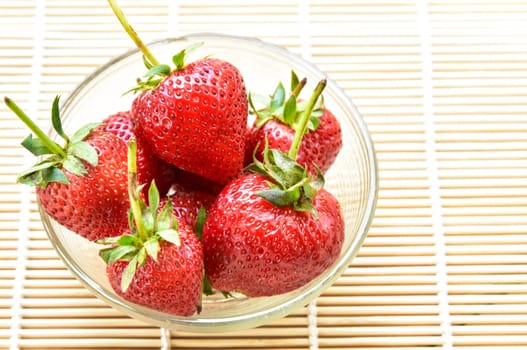 Fresh strawberries in a bowl on bamboo background