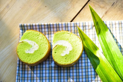 Pandan cream roll cake bakery pastry on fabric with cream and fresh Pandan leaf