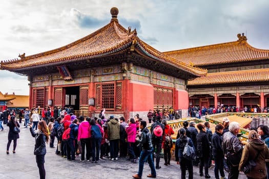 Beijing, China April 2013 Crowd of tourists visiting Forbidden City and taking pictures, front view on temples with golden roofs