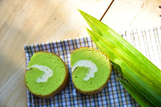 Pandan cream roll cake bakery pastry on fabric with cream and fresh Pandan leaf