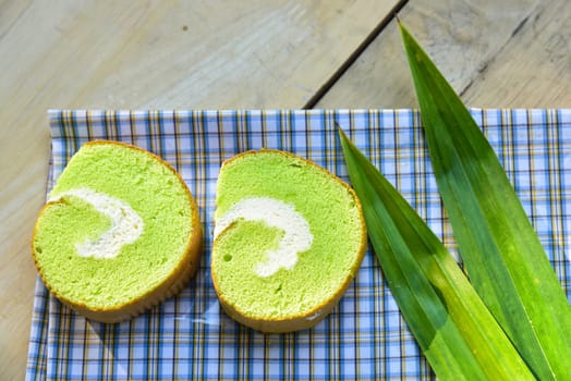Pandan cream roll cake bakery pastry on fabric with cream and fresh Pandan leaf