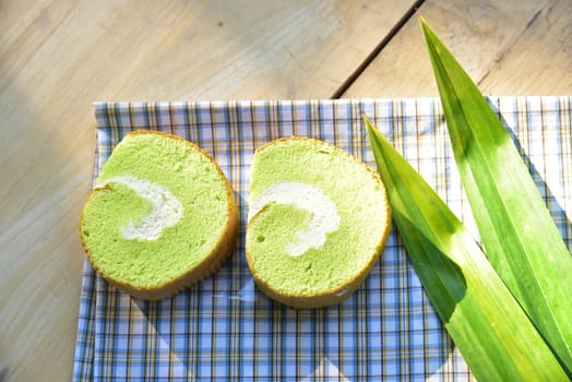 Pandan cream roll cake bakery pastry on fabric with cream and fresh Pandan leaf