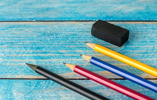 All pencil colorful sharpener and black esaer on blurred blue wooden table background