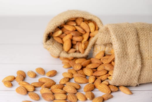 Almond in cloth bag on blurred white wooden table