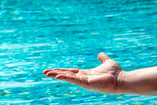 Flat hand against a wavy blue water background with reflections and copy space