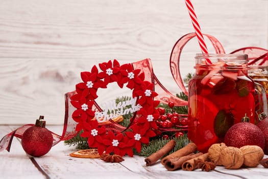 Winter holidays still life with fir tree branch, fruit tea, spices, nuts and oranges on a light wooden background with copy space. New Year and Christmas. Winter vacation.