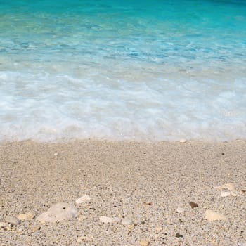 Tropical sand beach with sea waves and stones.