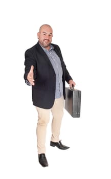 A handsome Hispanic business man with a briefcase standing and .stretching his hand out to great his customer, isolated for white.background.