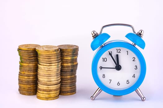 Clock and stacks of coins are close by, close-up