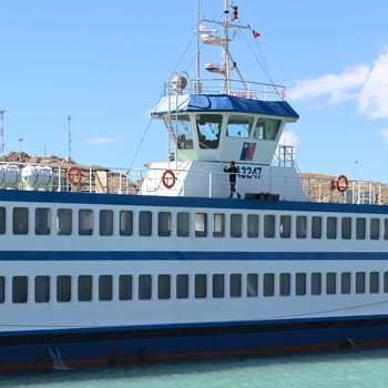 PUERTO IBANEZ, CHILE -FEBRUARY 20, 2016: Unidentified person walking with a mobile phone on the deck of a ferry in Puerto Ibanez, Chile on February 20, 2016. Puerto Ibanez is a small town on the Northern shore of Lago General Carrera, Chile's biggest lake.
