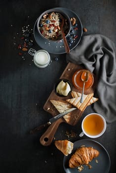 Breakfast served with oatmeal and fruits, croissants, jam and butter. Delicious healthy breakfast.