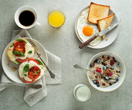 Breakfast served with oatmeal and fruits, mozzarella sandwich and fried egg with bread on table top view. Healthy breakfast food.