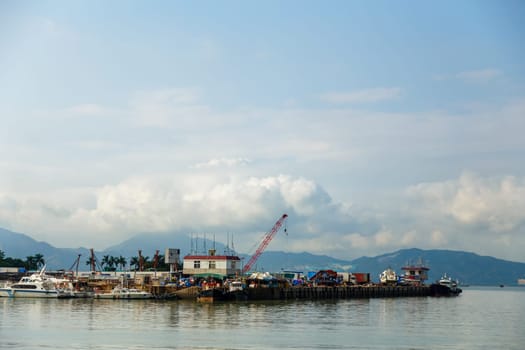 View of the fishing harbor in the bay against the backdrop of mountains and clouds on a clear morning, Shenzhen, China