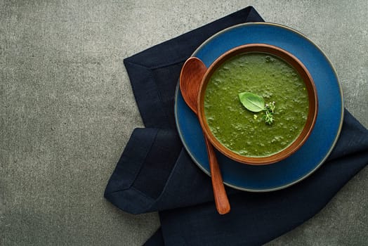 Eating spring healthy meal. Green creamy soup with vegetables and herbs