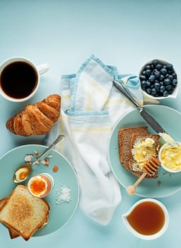 Breakfast served with coffee, croissant, egg, bread, honey and butter. Delicious healthy breakfast.