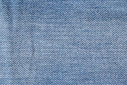 Denim background texture. Close-up of details of empty light blue jeans fabric jean surface. Macro. Top view. Beautiful backdrop.
