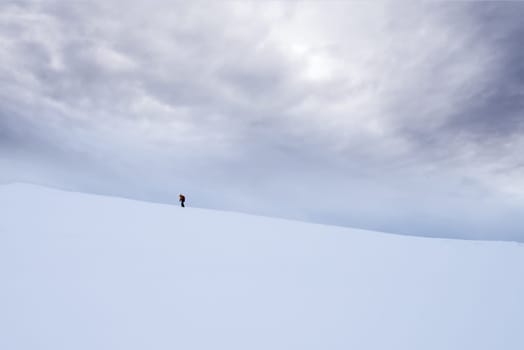 Unidentifiable person walking towards Storsteinen mountain summit and peak in the snow among the wonderful winter scenery, Norway