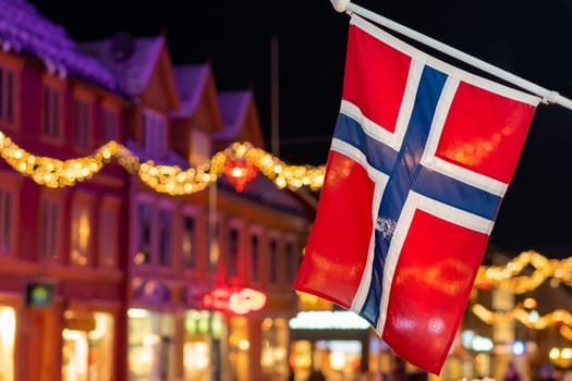 Norwegian flag hanging from a pole in Tromso city centre in Christmas period after dusk, Norway