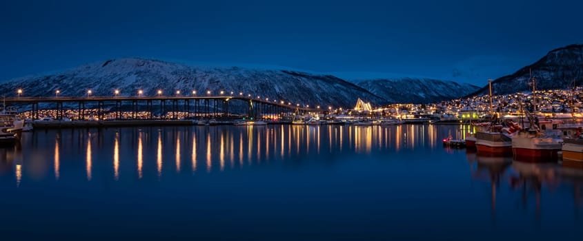Panorama of port and harbour with famous Tromso Bridge across Tromsoysundet strait in the background, photographed at night, Northern Norway