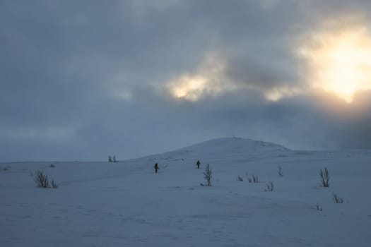 Unidentifiable people walking towards Storsteinen mountain summit and peak in the snow among the wonderful winter scenery, Norway