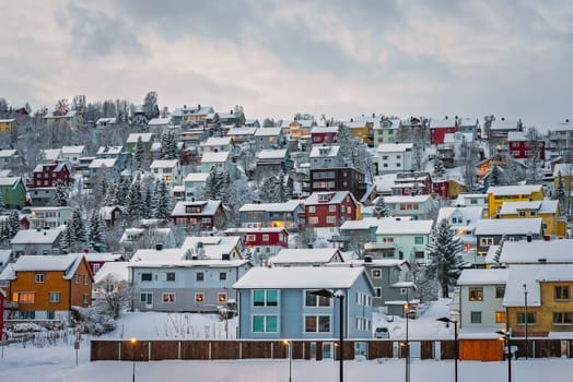 Residential hillside houses in Tromso suburb covered in a deep snow in winter, northern Norway