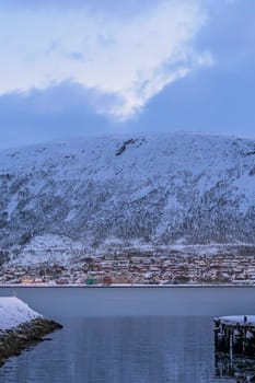 Residential hillside houses in Tromso suburb covered in a deep snow at dusk, Norway