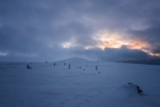 Unidentifiable people walking towards Storsteinen mountain summit and peak in the snow among the wonderful winter scenery, Norway