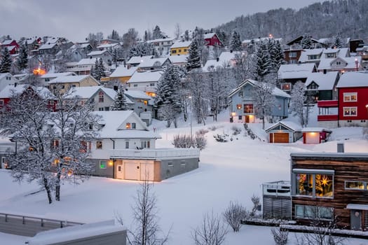 Residential hillside houses in Tromso suburb covered in a deep snow in winter, northern Norway