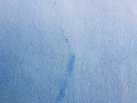 Blue lime coating texture on the old wall texture with a crack in the middle. Abstract rustic grunge plaster, stucco retro style.