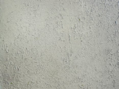 Grey paint peeling on a metallic surface background. Old grungy, weathered painted wall texture. Cracked, dirty, silver plaster falling off the construction structure.