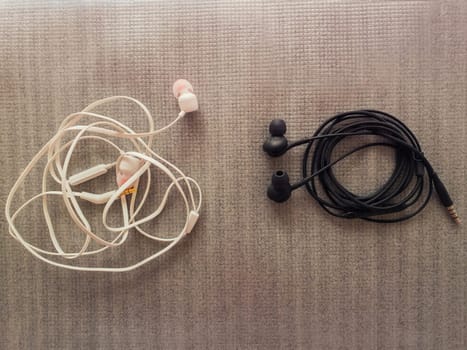 Two pairs of black and white wired headphones, for music listening. Wrap different ways, one is tangled while another neatly wrapped, as a characteristic of different human behavior, opposite concept.