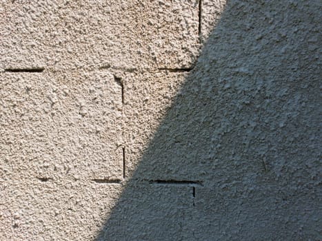 Old grey stone masonry wall texture made of foam blocks or airblocks split on two sides light and shadow. Abstract plastered surface. Grunge, weathered construction structure.