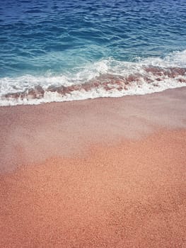Sand and water texture. Soft sea foam wave on the golden sandy beach. Summer holiday refreshment background.