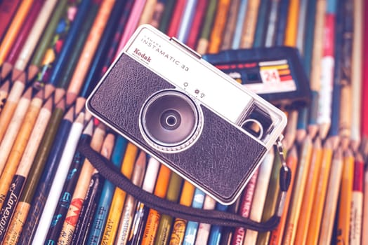 Old camera on top of old pencils, concept image of old and outdated but retro fashion.