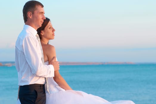 Beautiful wedding couple- bride and groom hugging at the beach. Just married