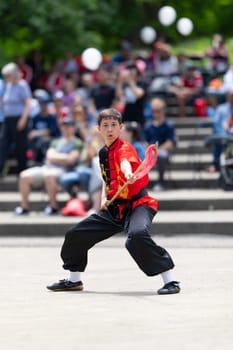 Columbus, Ohio, USA - May 26, 2019: Columbus Asian Festival, Franklin Park, Boy wearing traditional chinese clothing handling a Kung Fu Spear.