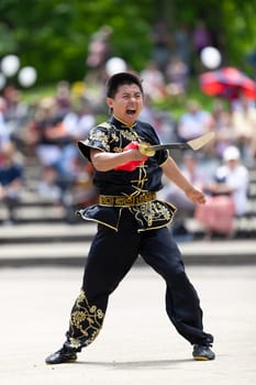 Columbus, Ohio, USA - May 26, 2019: Columbus Asian Festival, Franklin Park, Man wearing traditional chinese clothing handling a Kungfu broadsword during the festival