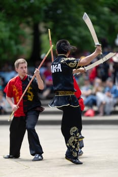 Columbus, Ohio, USA - May 26, 2019: Columbus Asian Festival, Franklin Park, Man using double Duilian Broadswords, fighting two men with Sticks