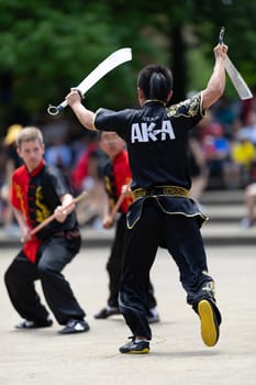 Columbus, Ohio, USA - May 26, 2019: Columbus Asian Festival, Franklin Park, Man using double Duilian Broadswords, fighting two men with Sticks