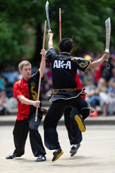 Columbus, Ohio, USA - May 26, 2019: Columbus Asian Festival, Franklin Park, Man using double Duilian Broadswords, fighting two men with Sticks