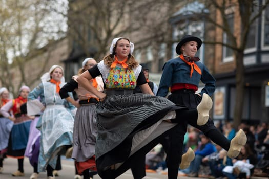 Holland, Michigan, USA - May 11, 2019: Tulip Time Festival, Young women wearing traditional Dutch Clothing dancing in the streets of Holland, Michigan during the Festival